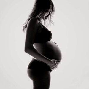 Donna incinta davanti a sfondo chiaro