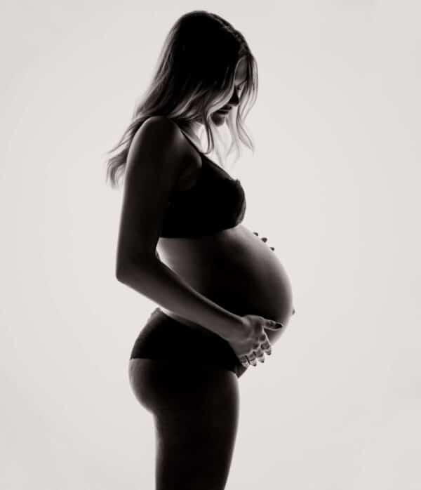 Donna incinta davanti a sfondo chiaro